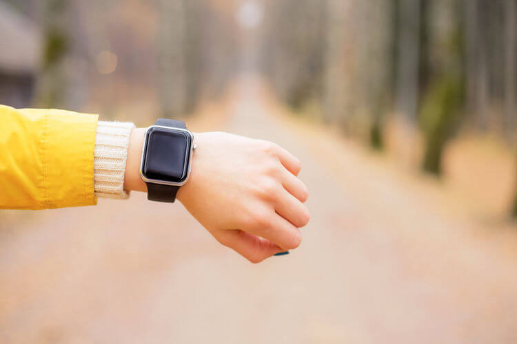 Woman looking at smart watch on a walk with yellow coat