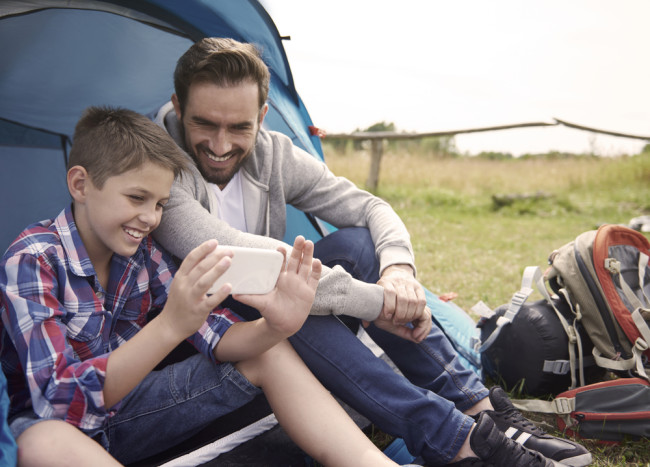 Dad and son using phone on a camping trip
