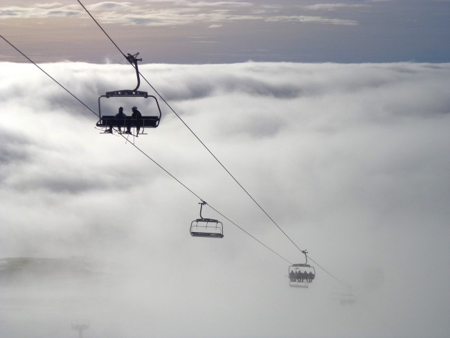 Skiers on ski lift up in the clouds