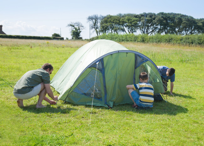 Family putting up a tent in a field