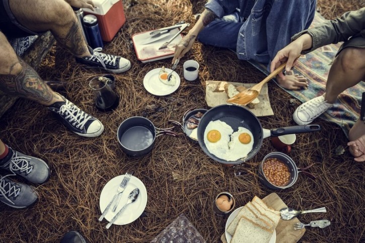 Group of friends cooking and eating at music festival